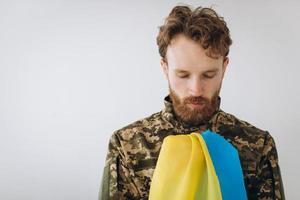 ukrainischer Patriot Soldat in Militäruniform mit einer gelben und blauen Flagge auf weißem Hintergrund foto