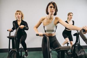 junger mann und frauen, die air bike für cardio-training im cross-trainingsstudio verwenden foto