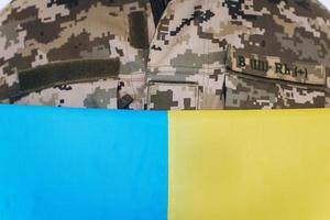 ukrainischer Patriot Soldat in Militäruniform mit einer gelben und blauen Flagge auf weißem Hintergrund foto