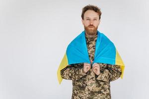 ukrainischer Patriot Soldat in Militäruniform mit einer gelben und blauen Flagge auf weißem Hintergrund foto