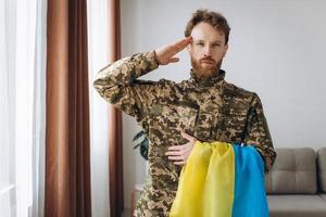 Porträt eines ukrainischen Soldaten in Militäruniform mit einer gelben und blauen Flagge zu Ehren foto