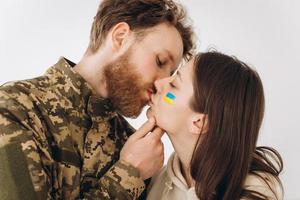 ukrainisches paar, militärbärtiger mann in uniform küsst seine freundin zu hause foto