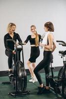 gruppe von frauen im fitnessstudio, die nach dem training im fitnessstudio auf airbikes miteinander trinkwasser sprechen foto