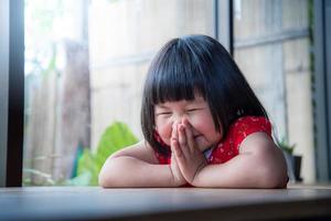 glückliches kleines Mädchen, das zu Hause betet, der reine Glaube des Kindes foto