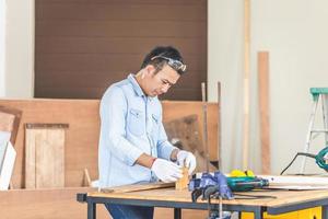 Tischler, der mit Ausrüstung auf Holztisch in der Holzwerkstatt arbeitet, Techniker, der Holzarbeiten in der Tischlerei macht foto