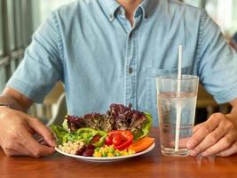 Mannhände, die einen grünen Salat halten. gesunder lebensstil und vegetarisch veganes, intermittierendes fastenkonzept. foto