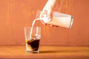 hand gießt milch zu gebrühtem kaffee im studio mit kopierraum. foto