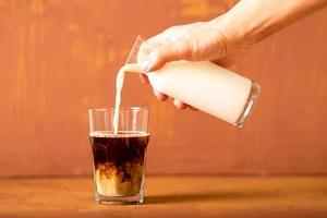 hand gießt milch zu gebrühtem kaffee im studio mit kopierraum. foto