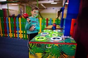 Junge spielt in Hit the Hamster Game Machine auf dem Indoor-Spielplatz. foto