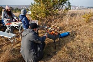 Familie beim Grillen auf einer Terrasse im Pinienwald. Grilltag mit Grill. foto