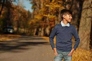 Junge Teenager tragen Poloshirt, blauen Pullover und Jeans im herbstlichen Hintergrund. foto