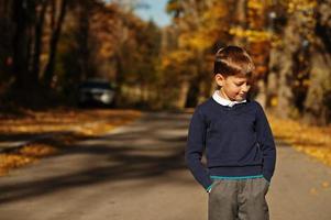 kleiner Junge trägt Poloshirt und klassischen Pullover im herbstlichen Hintergrund. foto