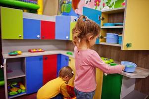 süße Schwestern spielen im Indoor-Spielzentrum. Kindergarten oder Vorschulspielzimmer. in der Kinderküche. foto