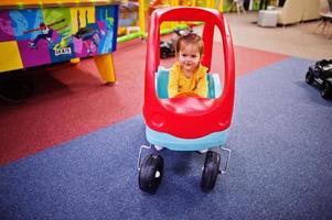 süßes kleines Mädchen fährt auf einem Plastikauto im Indoor-Spielzentrum. foto