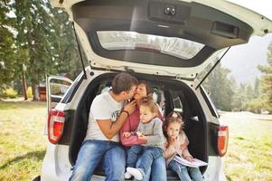 Familie mit zwei kleinen Mädchen im Fahrzeuginnenraum. Kinder im Kofferraum. reisen mit dem auto in den bergen, atmosphärenkonzept. foto