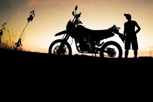 Herren-Silhouetten und Touren-Motocross-Bikes. Park zum Entspannen in den Bergen am Abend. abenteuerreise- und freizeitkonzept foto