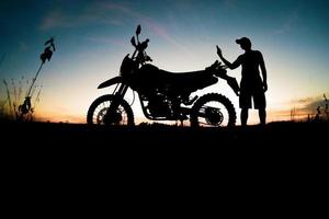 Herren-Silhouetten und Touren-Motocross-Bikes. Park zum Entspannen in den Bergen am Abend. abenteuerreise- und freizeitkonzept foto
