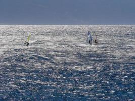 blaues wasser drei windsurfer strahlende sonne foto