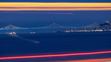 Bay Bridge in der Ferne mit Langzeitbelichtung Ampeln im Vordergrund foto