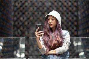 junge asiatische frau, die sms auf handy im einkaufszentrum sendet foto