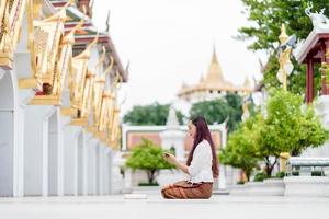 asiatische buddhistische frau, die traditionelles kleid von thailand trägt, sitzt und liest das alte tripitaka-buch von lord buddha dhamma in sanskrit foto