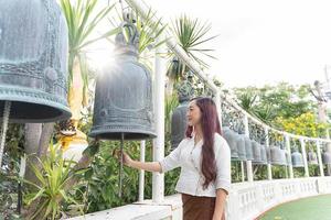 Asien-Frau, die traditionelle Kleidung von Thailand trägt, läutet für Glück im Wat Saket Ratcha Wora Maha Wihan foto