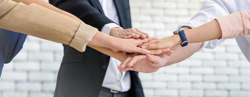 Nahaufnahme eines Geschäftsteams aus jungen Männern und Frauen, die mit ihren Händen Einheit zeigen, Einheitserfolg und Teamwork-Konzept. foto