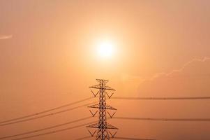 Hochspannungsmast, Sendeturm mit Stromleitung bei Sonnenuntergang foto