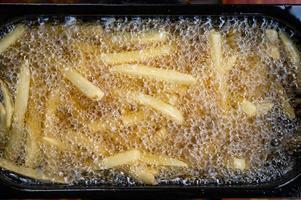 Pommes frites mit kochendem Öl in der elektrischen Friteuse braten foto