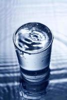 blaues monochromes Bild von Wasser, das in ein Glas spritzt. foto
