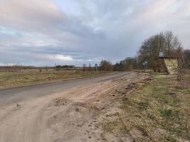 Frühlingsstraße durch das Feld zum Fluss foto