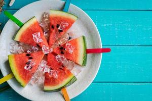 Wassermelonenscheibe Eis am Stiel mit buntem Stock auf Holzhintergrund, Sommerfrüchte foto