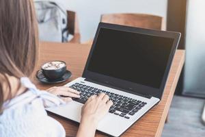 junge Frau mit Smartphone und Laptop mit Tasse Kaffee im Café foto