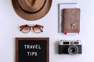 Retro-Kamera mit Spielzeugflugzeug, Karte und Reisepass auf weißem Hintergrund, Reisetipps-Konzept foto
