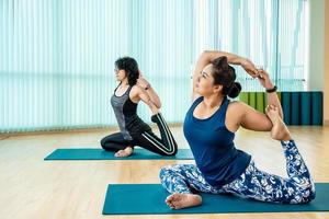 fitte Frau praktiziert Yoga mit Freunden, jung, Frau im Yoga-Kurs, die schöne Asana-Übungen macht. Mädchen machen Meerjungfrauen-Pose, Variation von Rajakapotasana. gesunder lebensstil im fitnessclub. foto