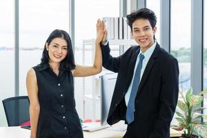 gut gemacht, lächelnde asiatische weibliche und männliche firmenkollegen, die im büro high five geben, aufgeregt über den beginn der partnerschaft foto