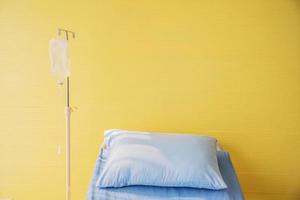 leeres Bett mit Kissen und Decke und intravenösem Ständer, Natriumchloridlösung für intravenöse, Sole, medizinische Behandlung, intravenöses Warten mit Kochsalzlösung für Patienten, Gesundheitsversorgung. foto