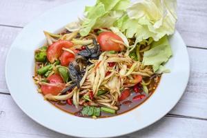 thailändisches Essen Papaya-Salat mit Kohlhof-Langbohnen auf weißem Teller, Papaya-Salat mit Krabben und fermentiertem Fisch foto