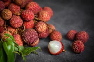 Litschi-Frucht mit grünem Blatt auf schwarzem Hintergrund, frische reife Litschi, die im Sommer vom Litschi-Baum bei tropischen Früchten Thailand geschält wird foto