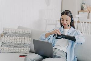 Behinderte kaukasische junge Frau im Headset hat eine Online-Konferenz auf dem Laptop. Gleichberechtigung. foto