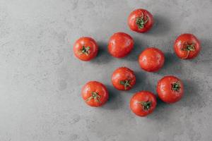 Köstliche rote Tomaten für die Herstellung von Ketchup auf grauem Hintergrund. Gemüse mit Wassertropfen bedeckt. Frische- und Ernährungskonzept. horizontaler Schuss foto