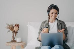 Fernunterricht zur Quarantäne. junge frau hat gruppenanruf über kopfhörer mit kaffee. foto