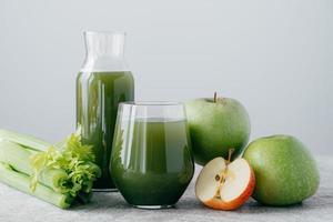 Foto von grünem Smoothie mit Cerely und Apfel in zwei Glasbehältern auf weißem Hintergrund. Gesunder Bio-Saft. Diät-Konzept.