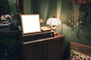 antiker audioplayer mit leerem rahmen und lampe, die auf holzschrank scheint foto