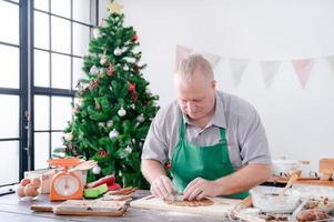 ein europäischer vater drückt die form auf den teig und bereitet die lebkuchenbackzutaten vor, die er und seine familie für weihnachten und neujahr backen foto