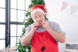 europäischer vater testet den geschmack von lebkuchen, den er und seine familie zu weihnachten und neujahr gebacken haben foto