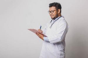 fröhlicher männlicher Arzt, der medizinische Notizen macht, die auf weißem Hintergrund mit Kopierraum isoliert sind foto
