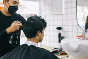 friseur, der die haare seines kunden im salon mit feuchtigkeitscreme besprüht foto