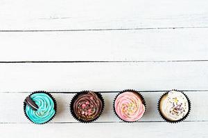 Leckere bunte Cupcakes isoliert auf Holzhintergrund. leckerer Kuchen foto