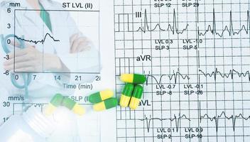 ekg- oder ekg-grafenberichtspapier. est-Ergebnis und grün-gelbe Kapselpillen mit Kardiologenfacharzt tragen weiße Uniform. arzt steht mit verschränkten armen und hand, die stethoskop hält. foto